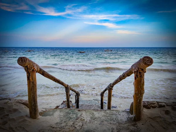 Escaleras de piedra al mar con barandilla de madera. Está en la playa de Diani en Kenia, África. Las olas en la marea alta bajan hasta las escaleras . — Foto de Stock