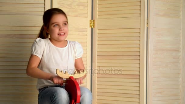 Маленькая девочка на деревянной лошади — стоковое видео
