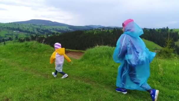 Flickor i regnrockar på ängen — Stockvideo