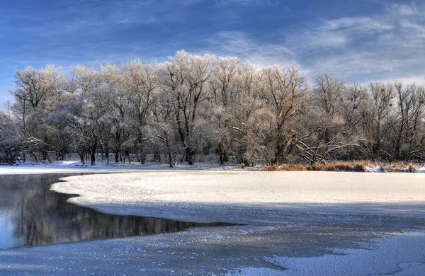 Lago parcialmente derretido no fundo de árvores nevadas — Fotografia de Stock
