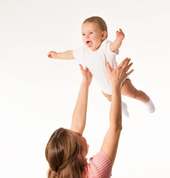 Jovem mãe feliz joga-se seu bebê encantador — Fotografia de Stock
