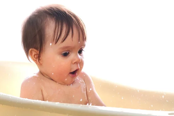 Little girl sits in the bath and splashes water — Stock Photo, Image