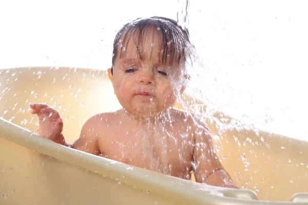 Bathing little baby girl under splashes of water — Stock Photo, Image