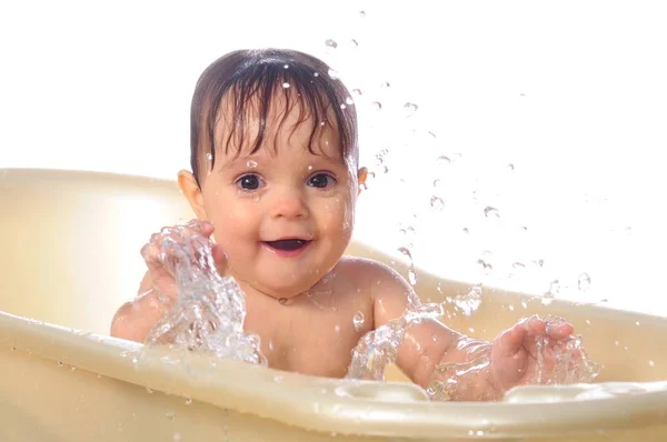 Happy baby girl under splashes of water in bath — Stock Photo, Image