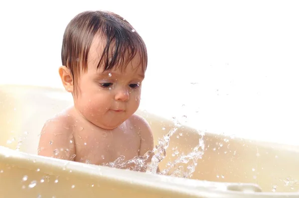 Little girl sits in the bath and splashes water — Stock Photo, Image