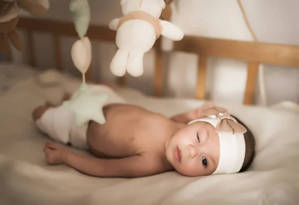 Yeni doğmuş bebek beşikte oyuncakların arasında yatıyor — Stok fotoğraf