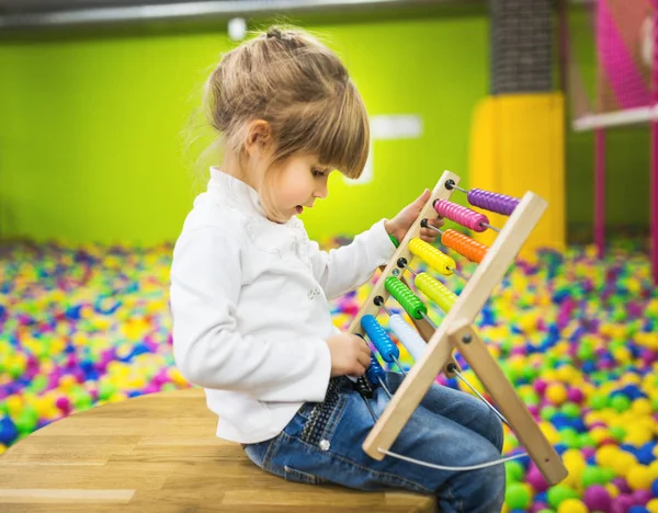 Menina brincando com um brinquedo de madeira abacus — Fotografia de Stock