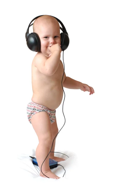 赤ちゃんはヘッドフォンの演奏で本物の音楽を聞く、彼はダンスをしようとする. — ストック写真