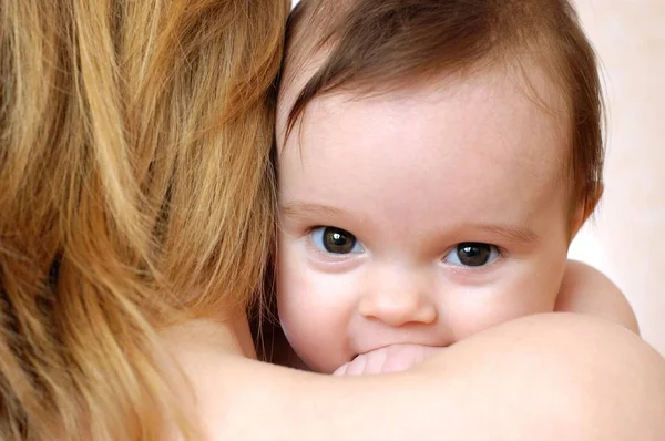Cute little baby uśmiecha się na ramieniu matek — Zdjęcie stockowe