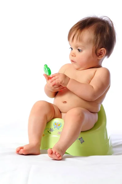 Baby sits on potty and plays toy — Stock Photo, Image