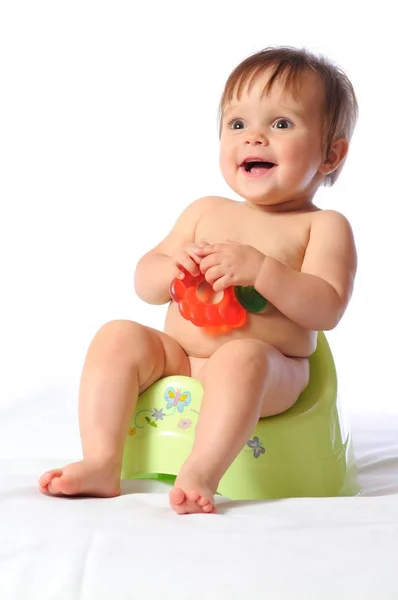 Pretty baby child sits on potty and holds teether — Stock Photo, Image