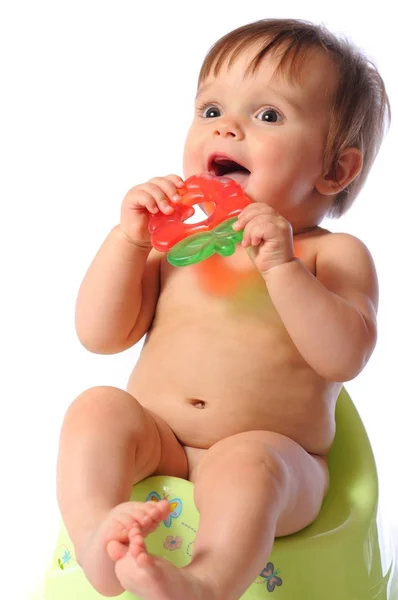 Pretty baby child sits on potty and holds teether — Stock Photo, Image
