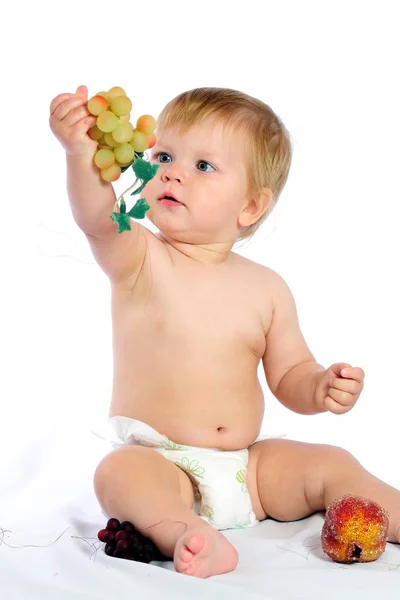 Junge sitzt neben Weidenkorb und hält Weintraube — Stockfoto