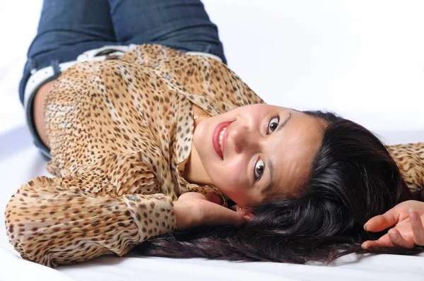 Brunette woman in leopard blouse looking at camera