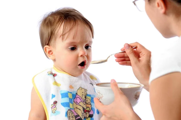 Mother feeds baby girl with spoon Stock Picture