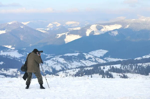 Photographer takes pictures from top of mountain