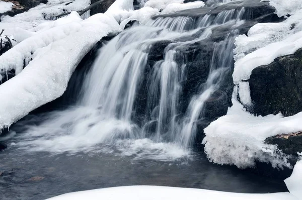 Una pequeña cascada de montaña cubierta de nieve — Foto de Stock