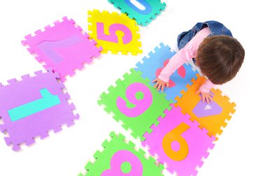 Küçük kız oturuyor, numaraları öğreniyor ve elinde tutuyor.