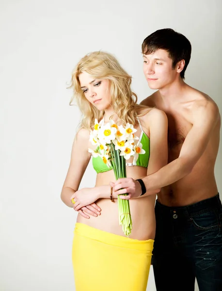 Jonge man presenteert bloemen aan blonde mooie vrouw in groene bikini — Stockfoto