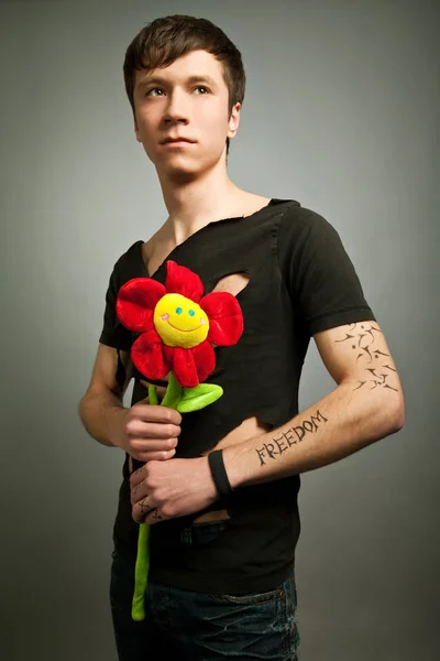 Modern siyah elbiseli genç adam elinde çiçek oyuncağı tutuyor. — Stok fotoğraf