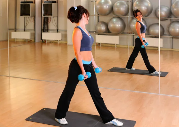 Femme debout avec haltères dans les mains sur tapis de yoga — Photo