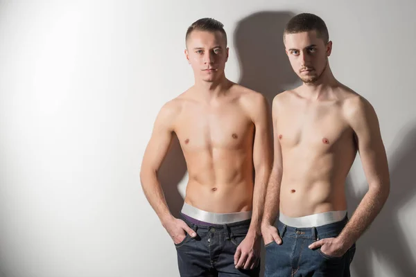 Jovens modelos lgbt em jeans e cuecas de pé e mostrando seus corpos — Fotografia de Stock