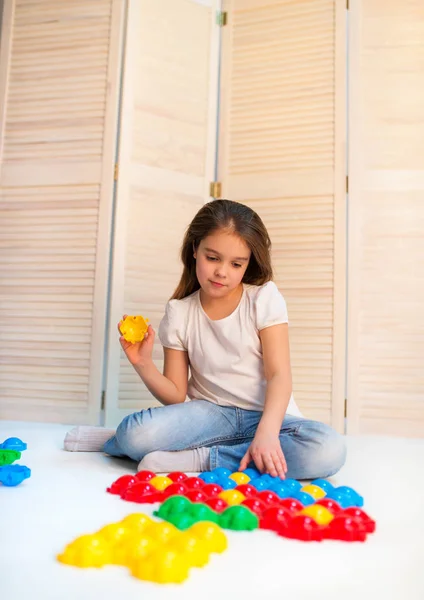 Маленька допитлива дівчинка відкладає пластикові головоломки — стокове фото
