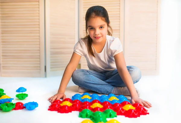 Маленька допитлива дівчинка відкладає пластикові головоломки — стокове фото