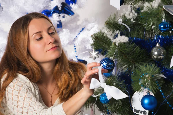 Çekici genç bayan Noel ağaçlarının yanında oturuyor. Telifsiz Stok Fotoğraflar