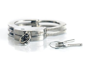 Metal kelepçeler ve anahtarlar beyaz arkaplanda izole edilmiş.