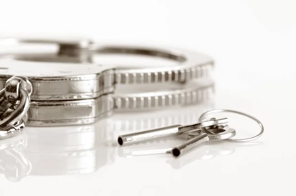 Handschellen und Schlüssel aus Metall isoliert über weißem Hintergrund — Stockfoto