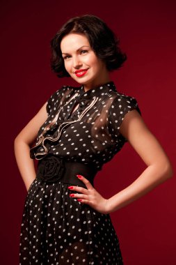 Kırmızı arka planda duran siyah elbiseli genç kadın.