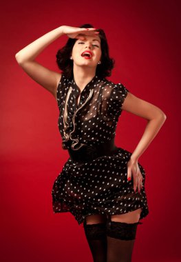 Kırmızı arka planda duran siyah elbiseli genç kadın.