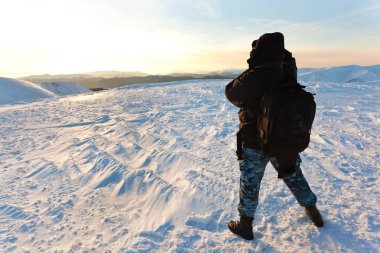 Kışın giyinmiş genç fotoğrafçı gün ışığında fotoğraf çekiyor.