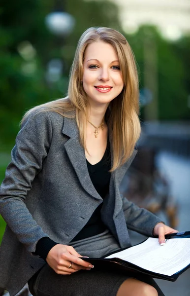 Portrait of young business lady sitting on bench with documents — Stock Photo, Image