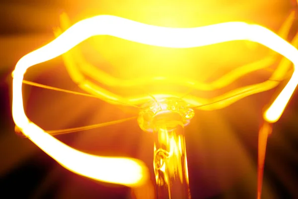 Close-up of burning light bulb with tungsten filament in center — Stock Photo, Image