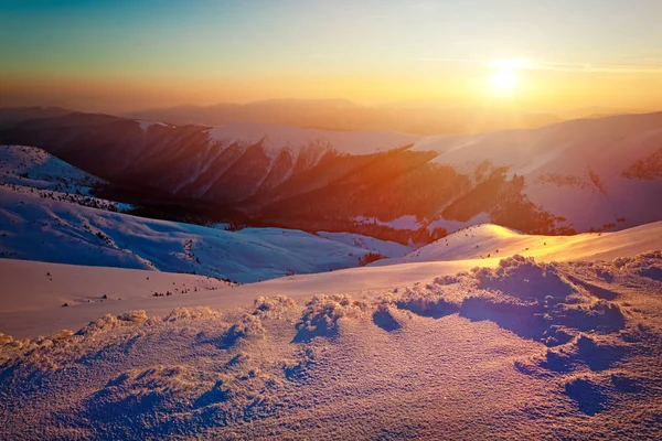 雪に覆われた冬の山の丘のパノラマの夕日の景色 — ストック写真