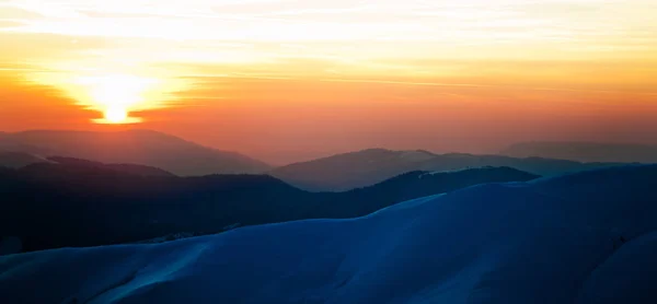 Panoramatický pohled na západ slunce na zimní horské kopce pokryté sněhem — Stock fotografie