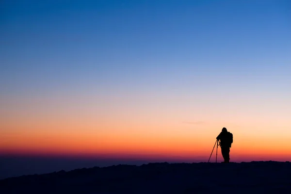 Silueta fotografului stând pe deal și făcând o fotografie a văii de seară — Fotografie, imagine de stoc