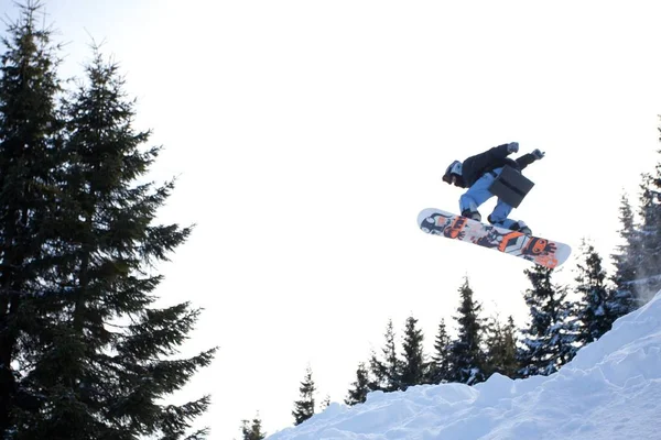 Giovane in abbigliamento sportivo che salta durante lo snowboard invernale — Foto Stock