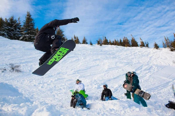 Junger Mann in Sportkleidung springt beim Snowboarden auf Schanzen — Stockfoto