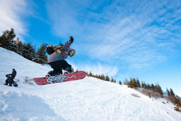 Jovem em sportswear jumping durante snowboard inverno em colinas — Fotografia de Stock