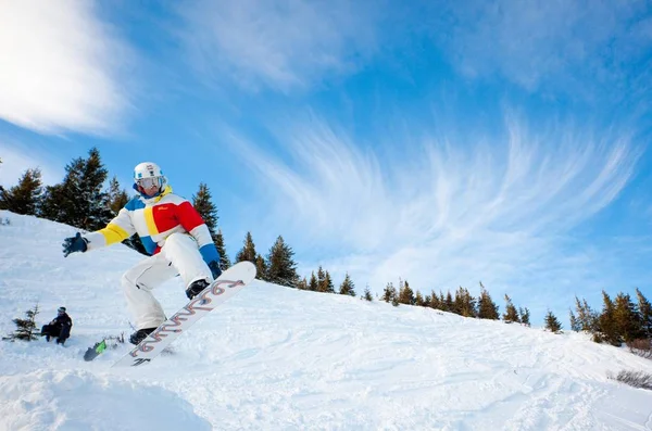Fiatal férfi sportruházat snowboard felett fenyőfák háttér — Stock Fotó