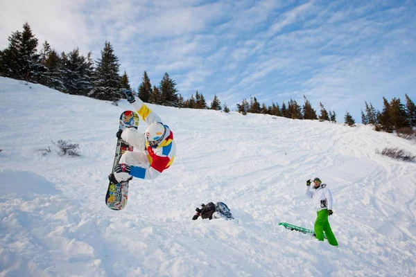 Fotógrafo fazendo foto de jovem em sportswear jumping durante snowboard — Fotografia de Stock