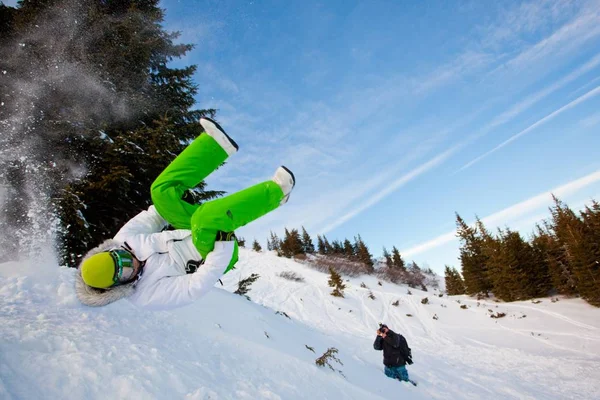 Fotografo che fotografa il giovane in abbigliamento sportivo che salta durante lo snowboard — Foto Stock