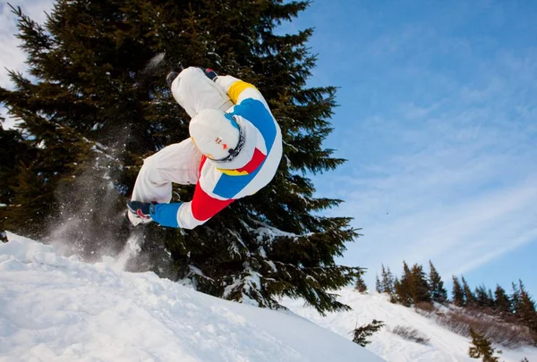 Junger Mann in Sportkleidung beim Snowboarden über Kiefern — Stockfoto