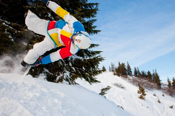 Junger Mann in Sportkleidung beim Snowboarden über Kiefern — Stockfoto