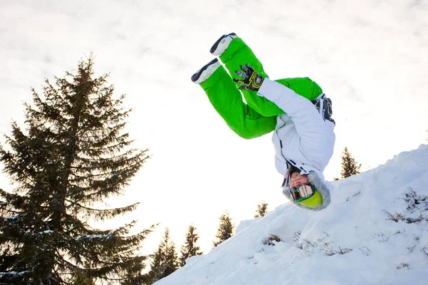 Jongeman in sportkleding springen tijdens de winter snowboarden — Stockfoto