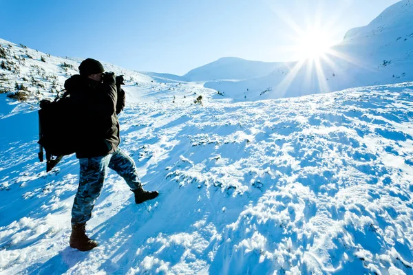 Kışın giyinmiş genç fotoğrafçı gün ışığında fotoğraf çekiyor.