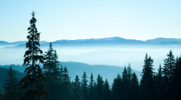Panoramatický výhled na zimní kopce a údolí pokryté sněhem a bílým kouřem — Stock fotografie